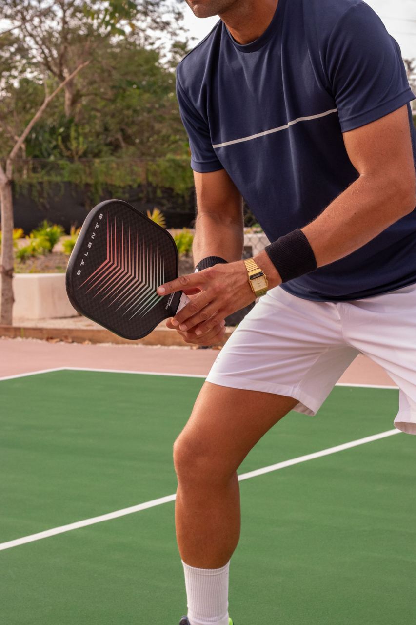 Pickleball player holding a paddle on an outdoor court, illustrative stock photograph