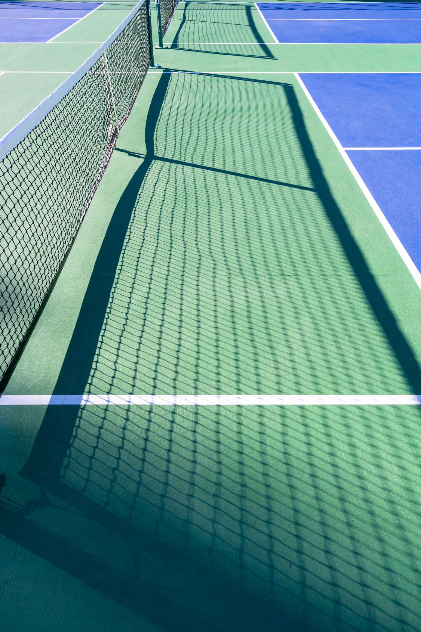 Empty outdoor pickleball courts and net shadows, illustrative stock photograph